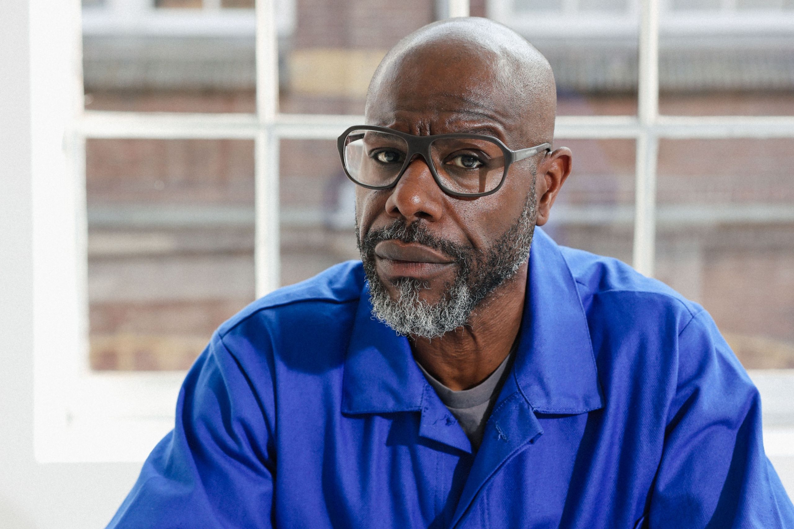 Steve McQueen award winner Erasmus Prize 2026. Steve McQueen dressed in blue with city scape background beyond the window.